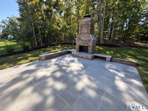Outdoor living - Spacious bluestone patio with a brick outdoor fireplace, built-in benches, and landscaping