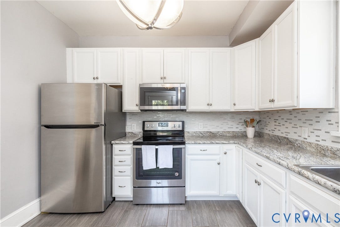 Kitchen featuring white shaker-style cabinetry, stainless steel appliances, granite countertops, and a mosaic tile backsplash