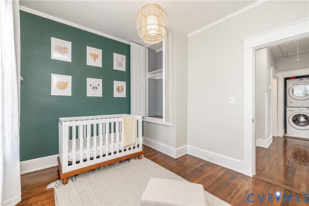 Room featuring wood-finish flooring, a decorative light fixture, and a built-in storage area with shutters