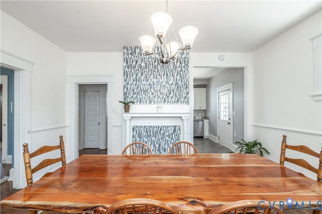 Dining space featuring a decorative fireplace mantel with patterned tile accent, chair rail molding, and a five-light chandelier