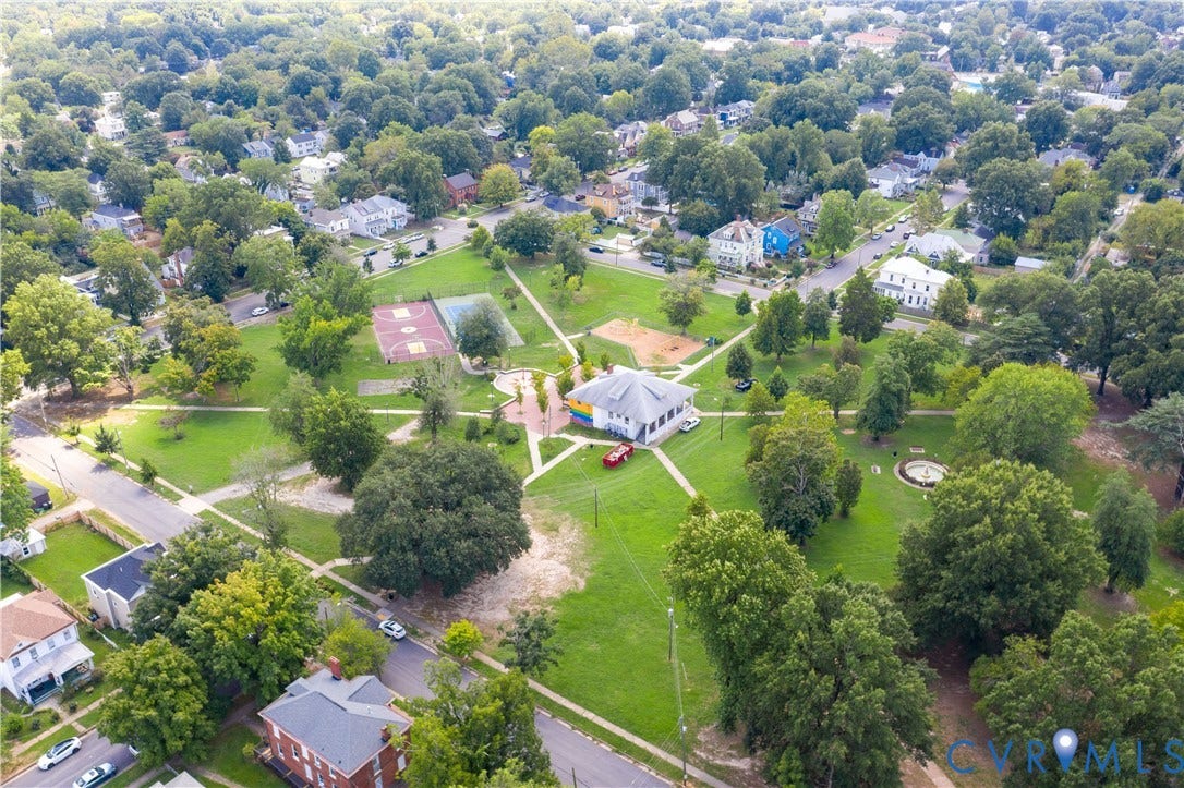 Spacious park area featuring a white recreational building, multiple sports courts, and mature trees