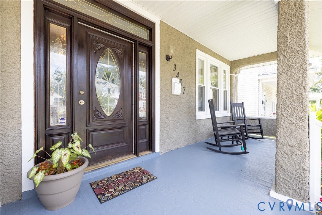 Inviting covered front porch with a paneled entry door, decorative glass sidelights, and a transom window