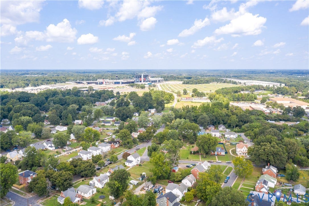 Suburban neighborhood featuring varied residential architecture, mature tree canopy, and proximity to a large stadium structure