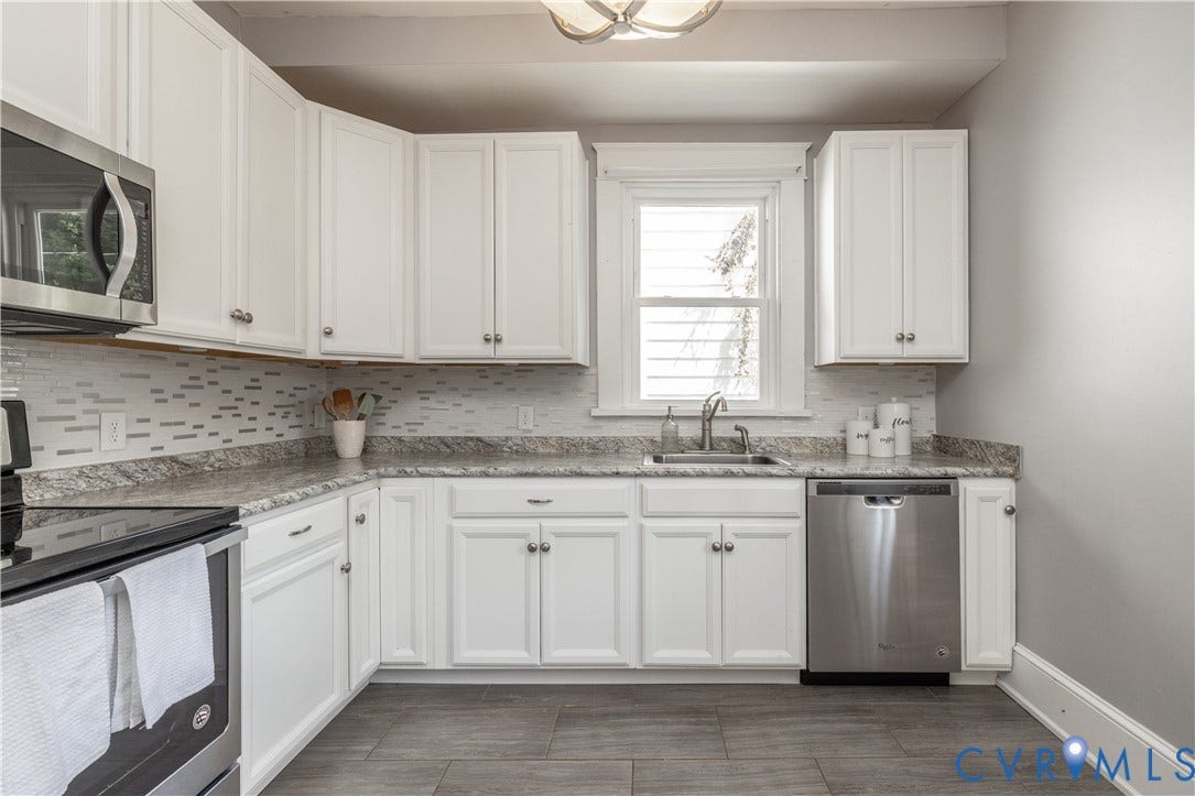 Kitchen featuring white cabinetry, patterned countertops, and a mosaic tile backsplash