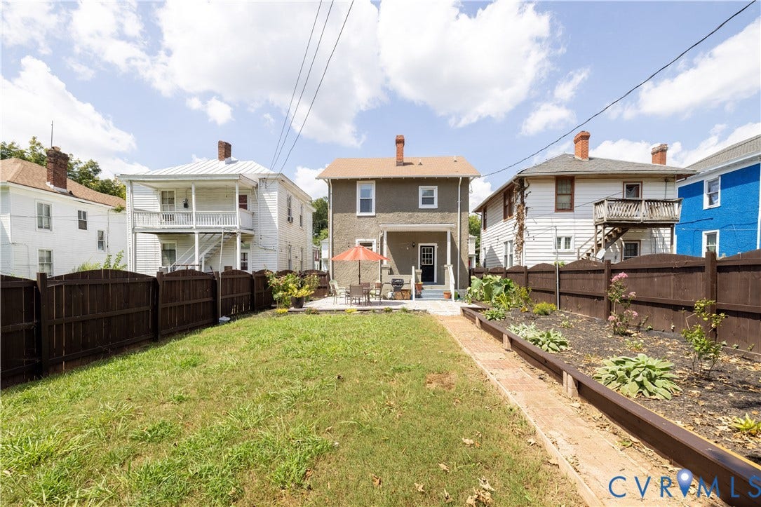 Expansive backyard featuring a lush lawn, a brick paver pathway, and a large patio area