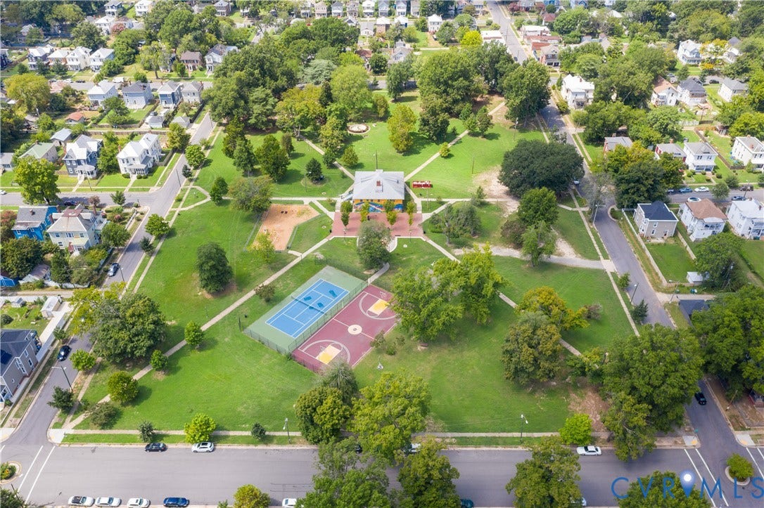 Expansive park setting surrounded by residential properties, featuring mature trees and a manicured lawn