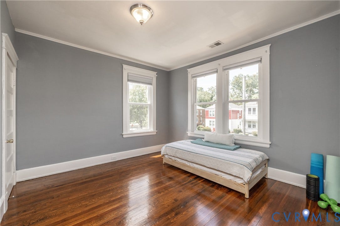 Hardwood flooring throughout featuring white baseboards, crown molding, and door trim