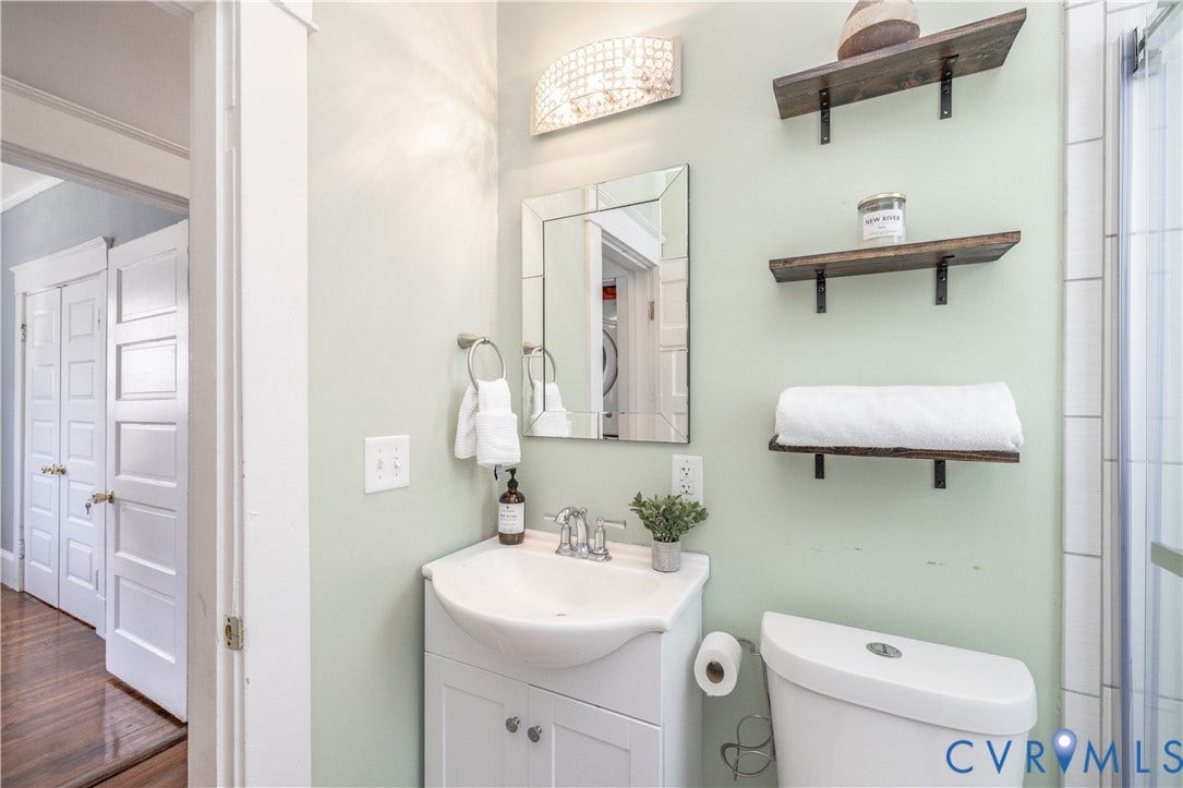 Bathroom featuring a vanity with an integrated sink, a frameless mirror, and a decorative wall sconce
