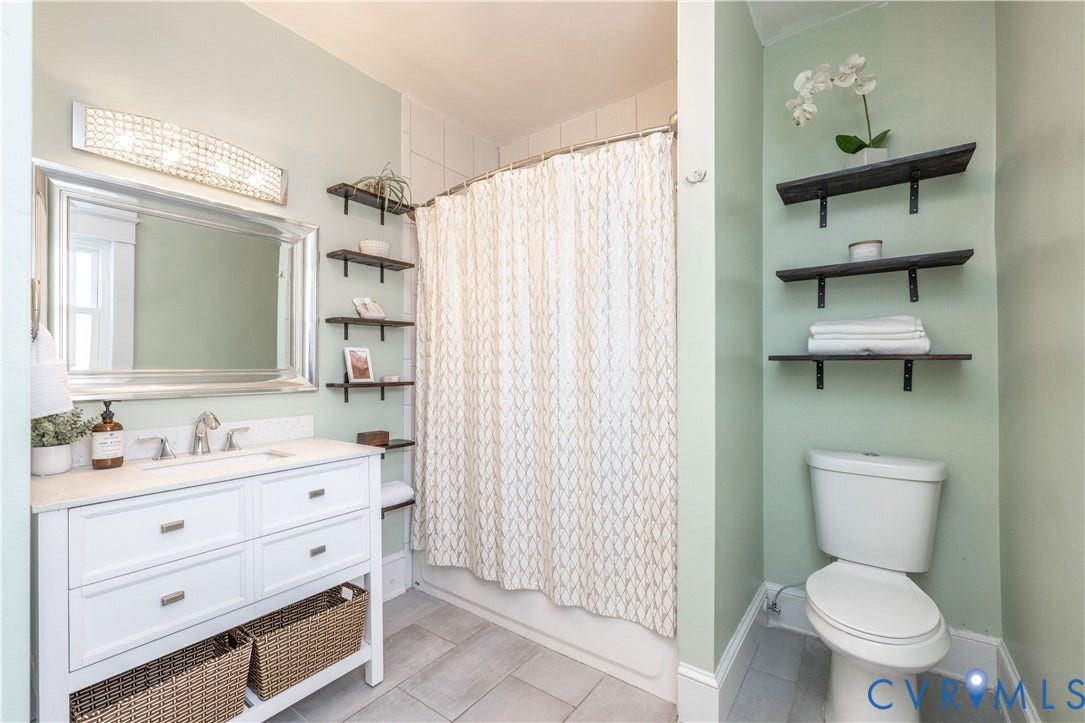 Bathroom featuring a white vanity with a light-toned countertop, a large framed mirror, and a crystal-detail light fixture