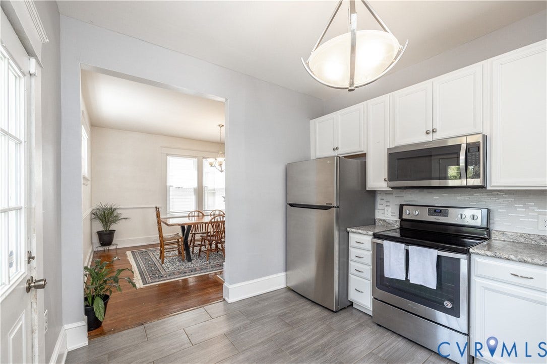 Kitchen featuring stainless steel appliances, white cabinetry, tile backsplash