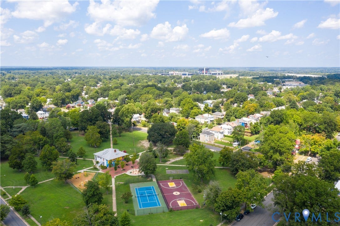 Expansive green space featuring a central building, multiple sports courts, and mature trees