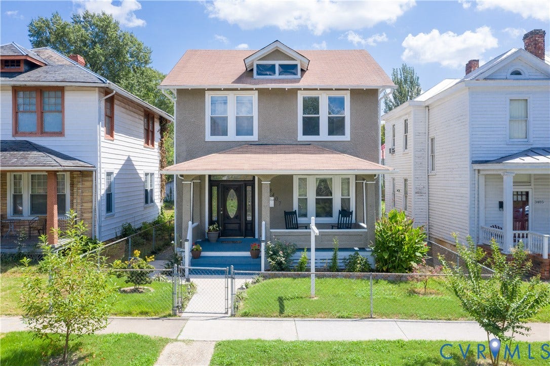 Two-story residence featuring a covered front porch, dormer window, and an enclosed front yard