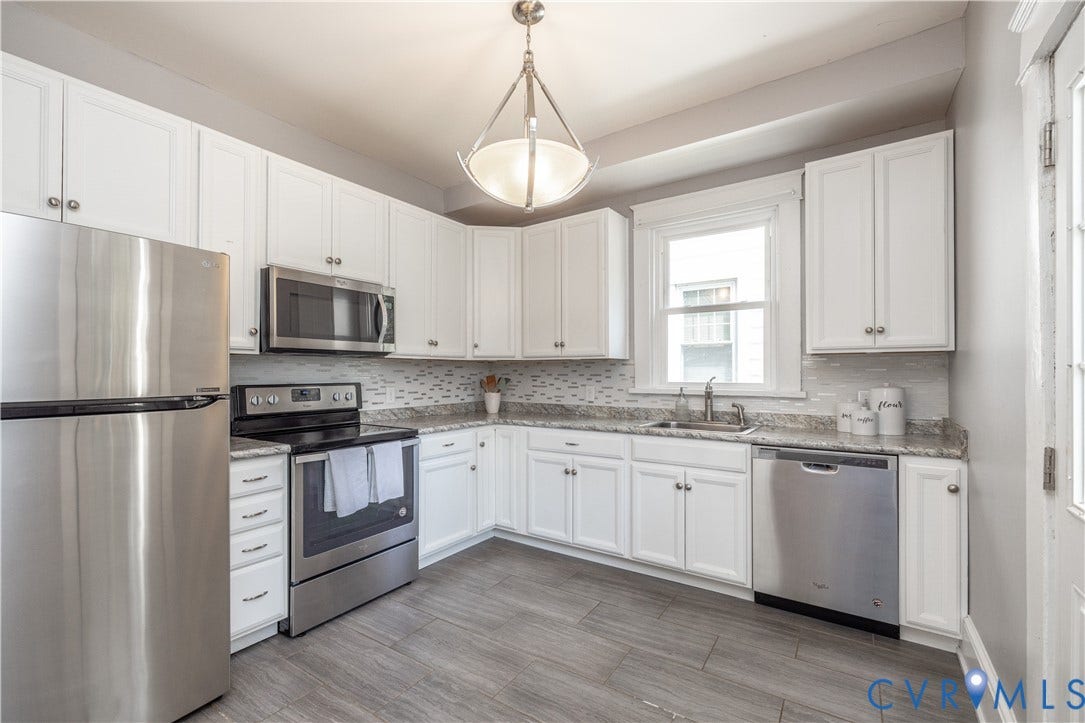 Kitchen featuring white cabinetry, stainless steel appliances, granite countertops, and a subway tile backsplash