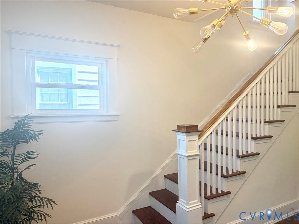Staircase featuring wood-finish treads, white risers, and a wood-finish handrail