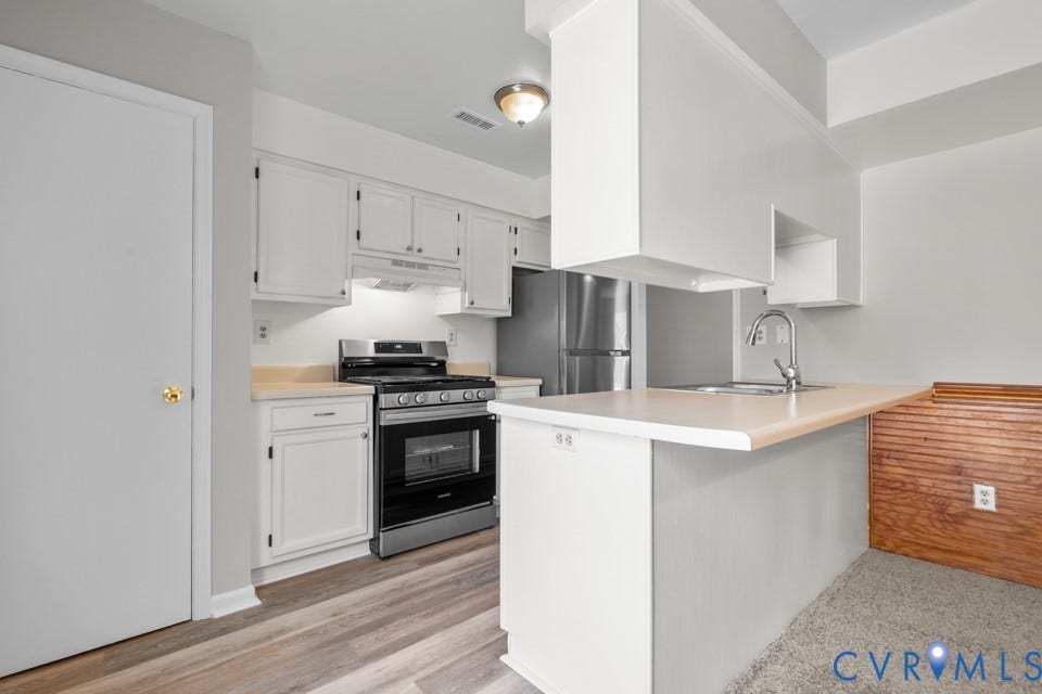 1409 Idlewood Avenue, Randolph, Richmond, VA 23220 Kitchen featuring white cabinetry, stainless steel appliances, wood-finish flooring, a breakfast bar, and a single-basin sink with a gooseneck faucet