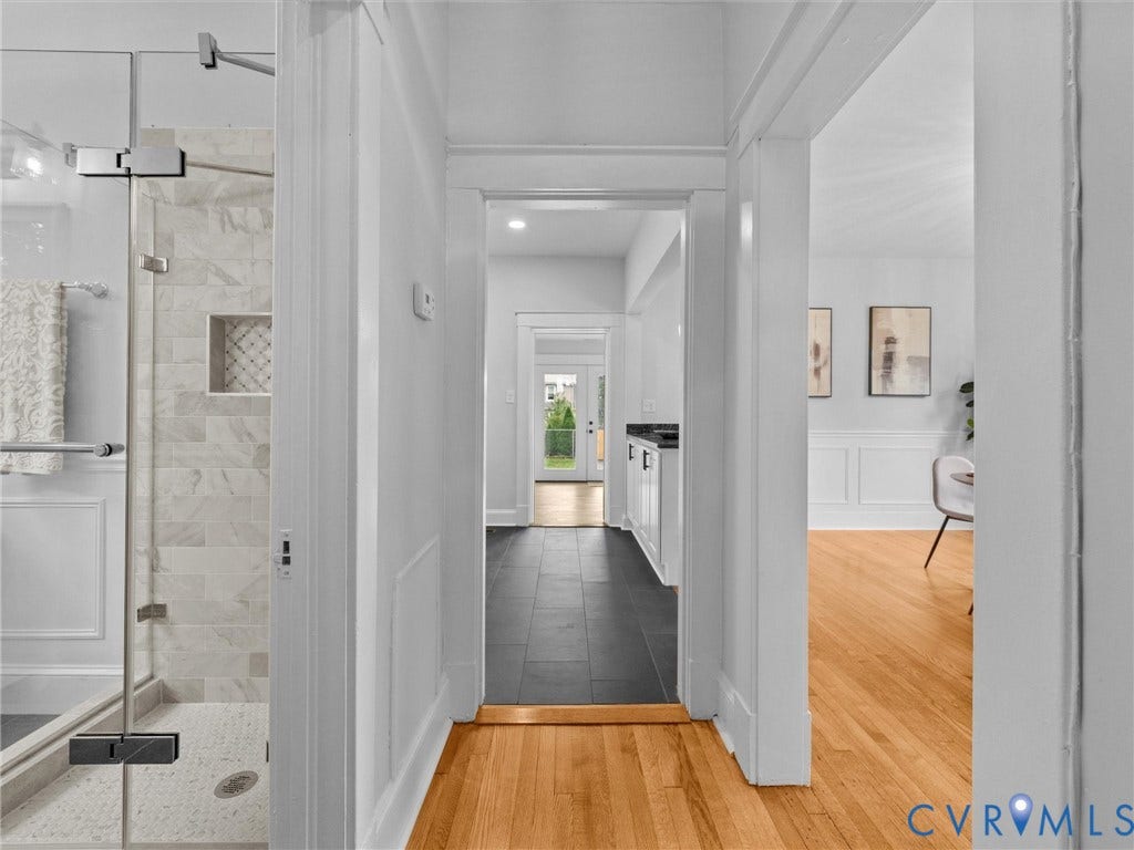 2911 Northumberland Avenue, Northside, Richmond, VA 23220 Hardwood flooring extends through the hallway with white trim, leading to a modern bathroom featuring a glass-enclosed shower with tiled walls and a decorative niche