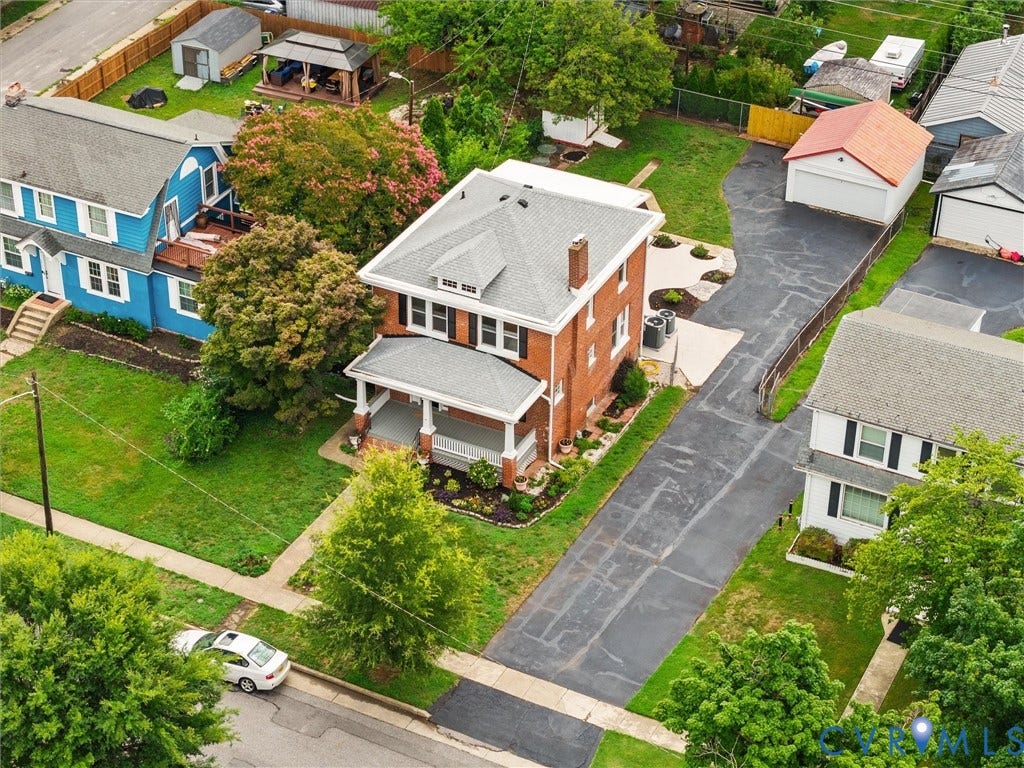 2911 Northumberland Avenue, Northside, Richmond, VA 23220 Brick residence featuring a covered front porch with white columns, a long paved driveway, and a detached garage with a red roof