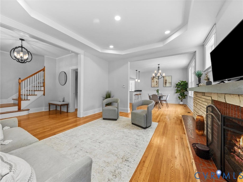 2911 Northumberland Avenue, Northside, Richmond, VA 23220 Spacious living area featuring hardwood flooring, a stone and brick fireplace, tray ceilings with recessed lighting, and a prominent staircase with wood newel posts and white balusters