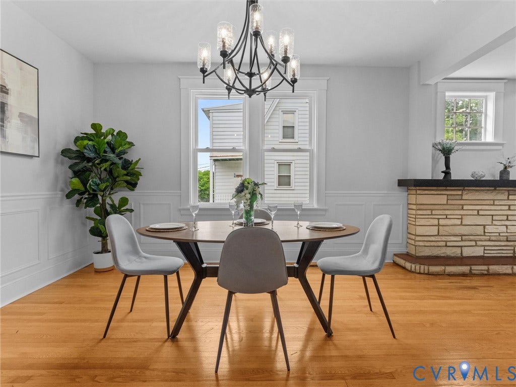 2911 Northumberland Avenue, Northside, Richmond, VA 23220 Dining area featuring wood-finish flooring, wainscoting, an exposed stone hearth with black mantel, and a contemporary chandelier