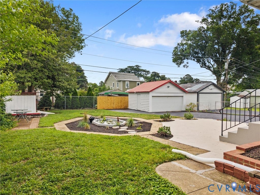 2911 Northumberland Avenue, Northside, Richmond, VA 23220 Expansive backyard featuring a central water feature, a paved patio area, and a separate asphalt driveway leading to two detached garages