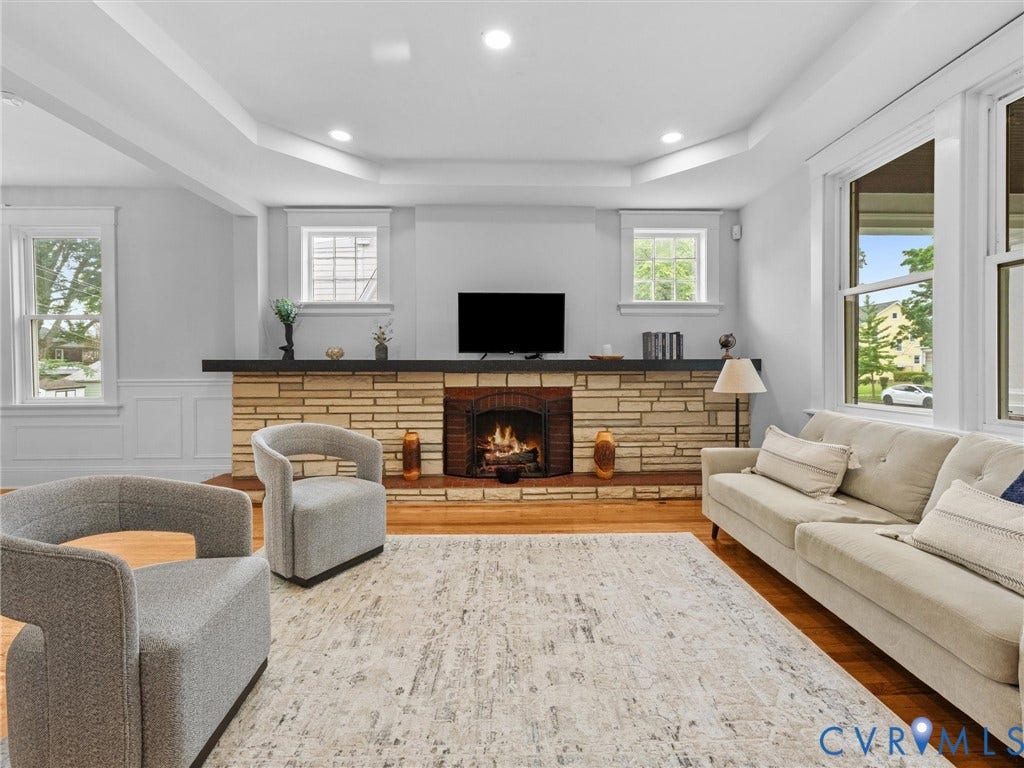 2911 Northumberland Avenue, Northside, Richmond, VA 23220 Spacious living area featuring a stone-clad fireplace with a dark mantel, wood-finish flooring, and bright windows
