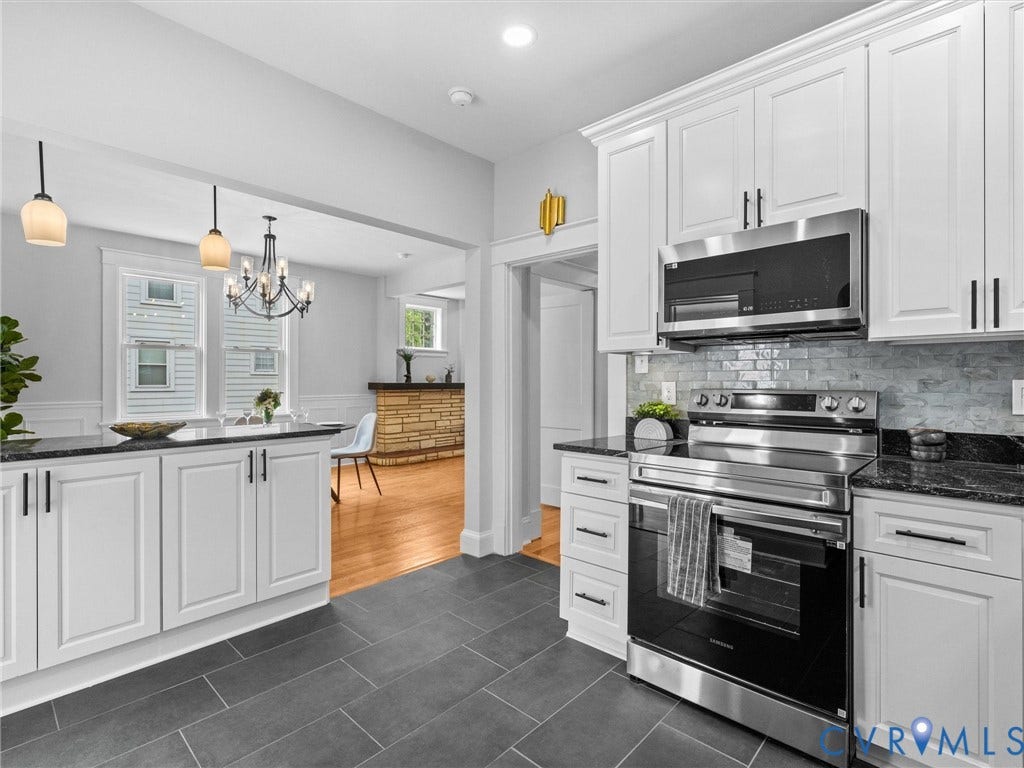 2911 Northumberland Avenue, Northside, Richmond, VA 23220 Modern kitchen featuring white shaker cabinetry, stainless steel appliances, dark granite countertops, a tiled backsplash, and dark gray tile flooring