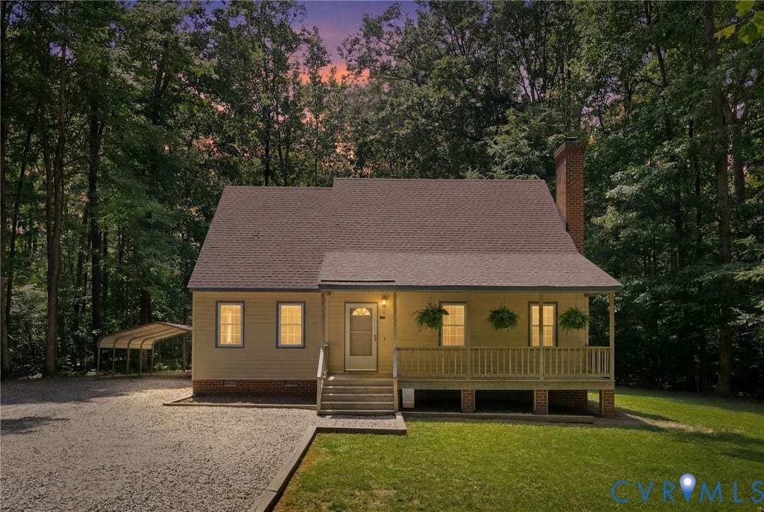 Light yellow siding home with a dark shingle roof and a front porch featuring a wooden railing