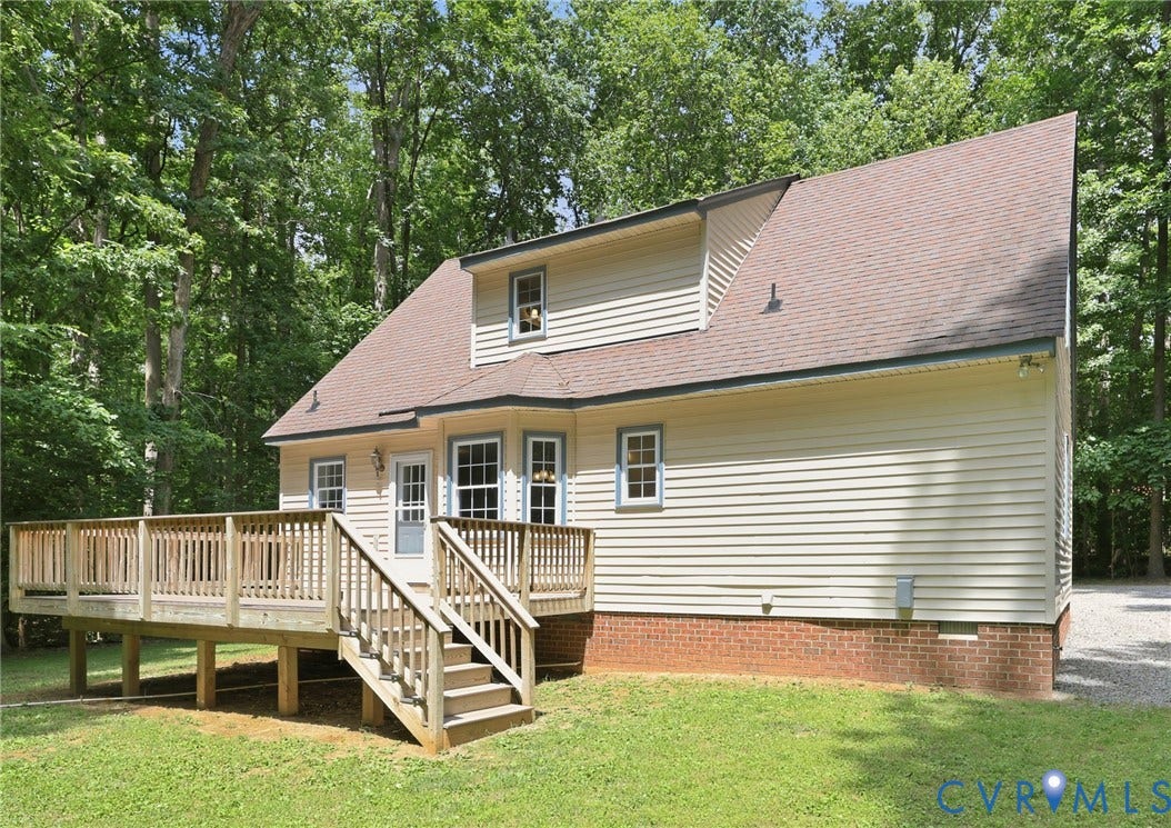 Expansive rear wood deck with balustrade railing, offering outdoor access through a glass-paneled door