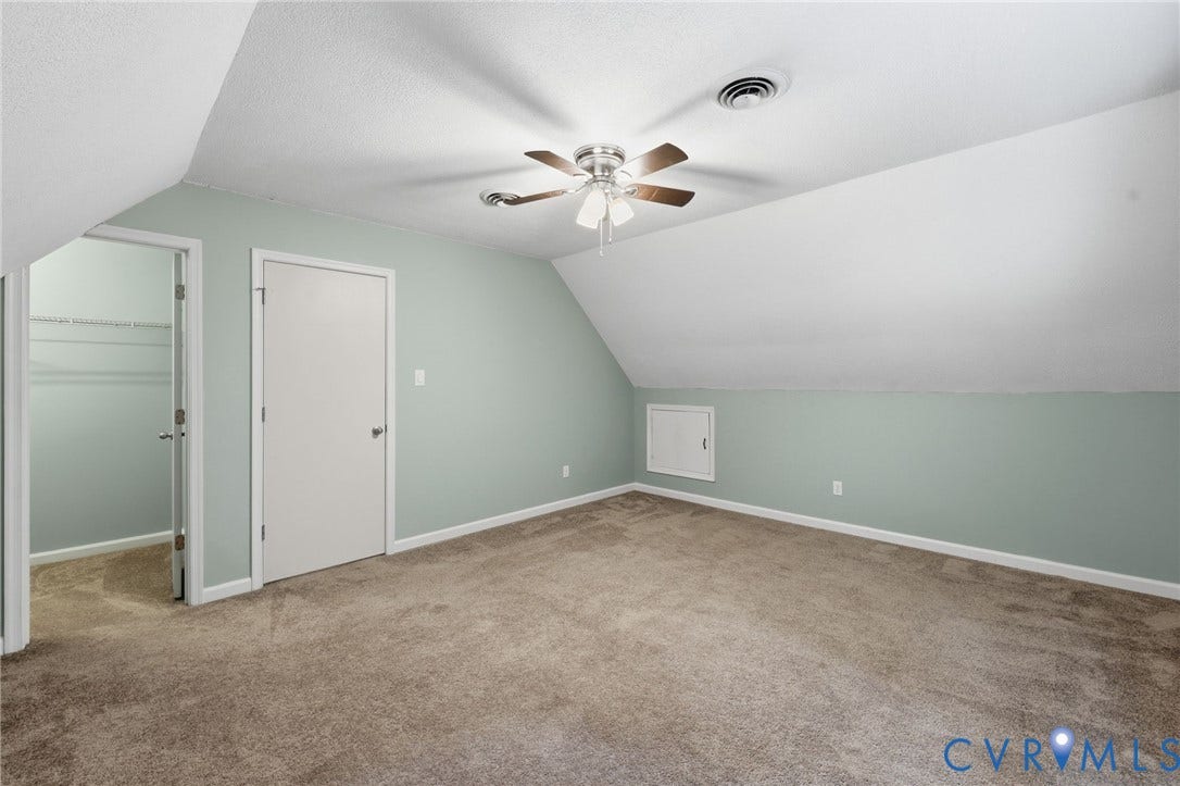 Carpeted room featuring a sloped ceiling, ceiling fan with light fixture, and pale green walls