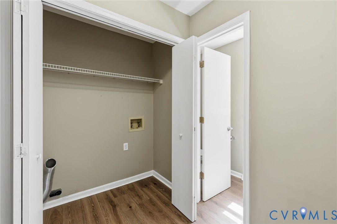 Dedicated laundry area featuring wood-finish flooring, white wire shelving, neutral wall paint, and white trim
