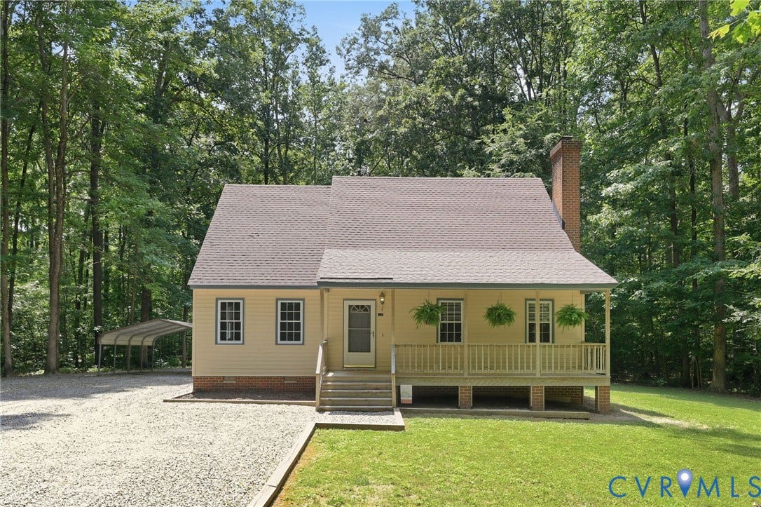 Traditional-style home featuring a covered front porch, light yellow siding, and a prominent brick chimney
