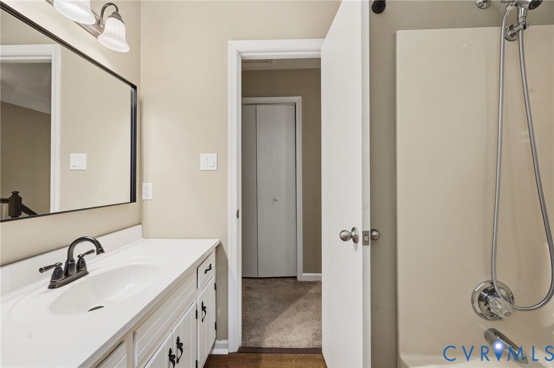 Bathroom featuring a white vanity with integrated sink, dark bronze-finish faucet, and coordinating cabinet hardware