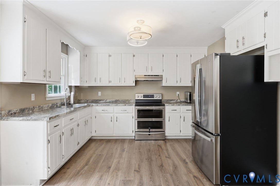 Kitchen featuring white cabinetry, wood-finish flooring, stainless steel appliances, a double oven, and speckled countertops