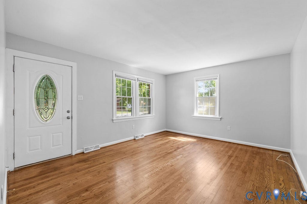 5527 Hansdale Road, Piney Knolls, Richmond, VA 23224 Entryway featuring a white door with an oval-shaped stained glass insert, wood-finish flooring, two large windows with white trim, and light gray painted walls
