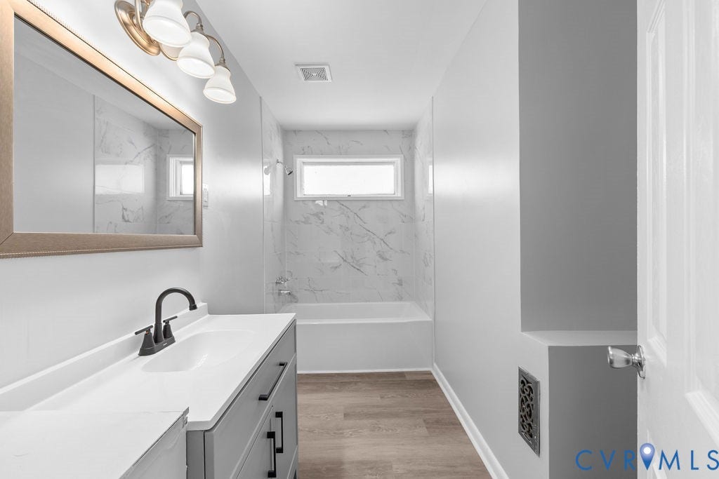 5527 Hansdale Road, Piney Knolls, Richmond, VA 23224 Bathroom featuring a single vanity with gray cabinetry and white countertop, a bronze-framed mirror, and a three-light vanity fixture