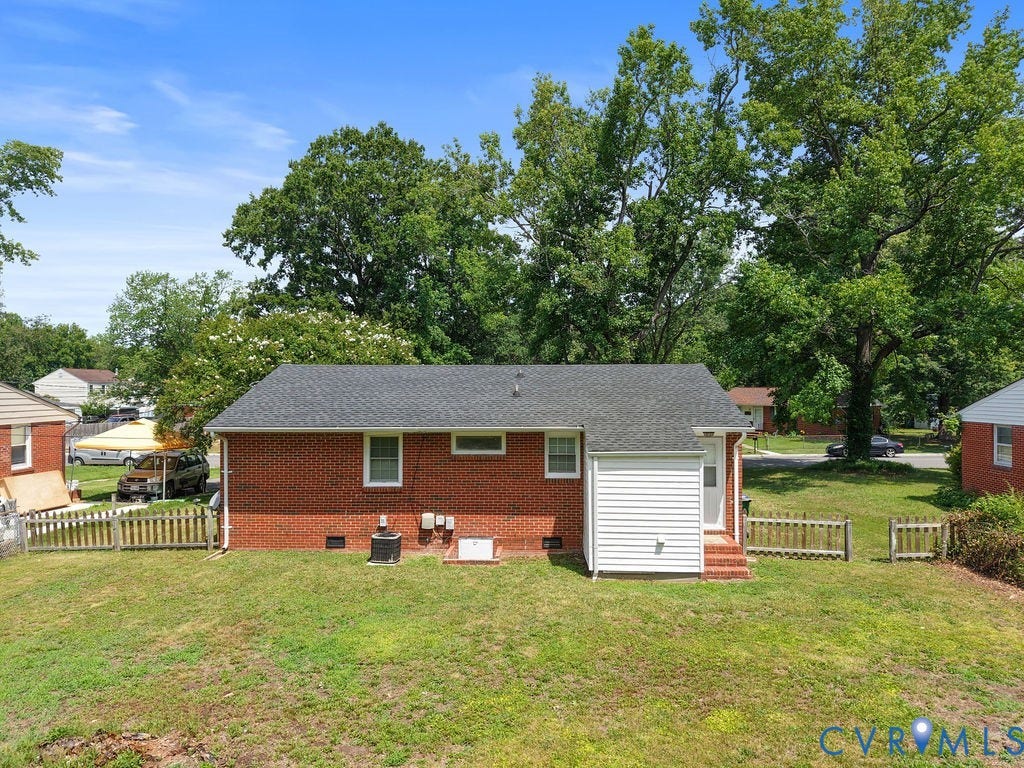 5527 Hansdale Road, Piney Knolls, Richmond, VA 23224 Rear exterior featuring a brick facade, white vinyl siding extension, and a dark shingle roof