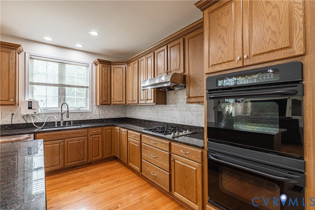 16814 Jennway Place, Moseley, VA 23120 Kitchen featuring wood cabinetry, dark countertops, a tile backsplash, and wood-finish flooring