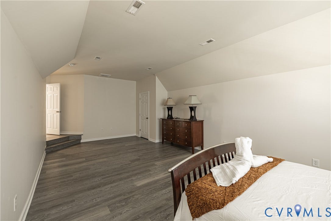 16814 Jennway Place, Moseley, VA 23120 Spacious room featuring vaulted ceilings, recessed lighting, wood-finish flooring, white trim, and a white paneled door