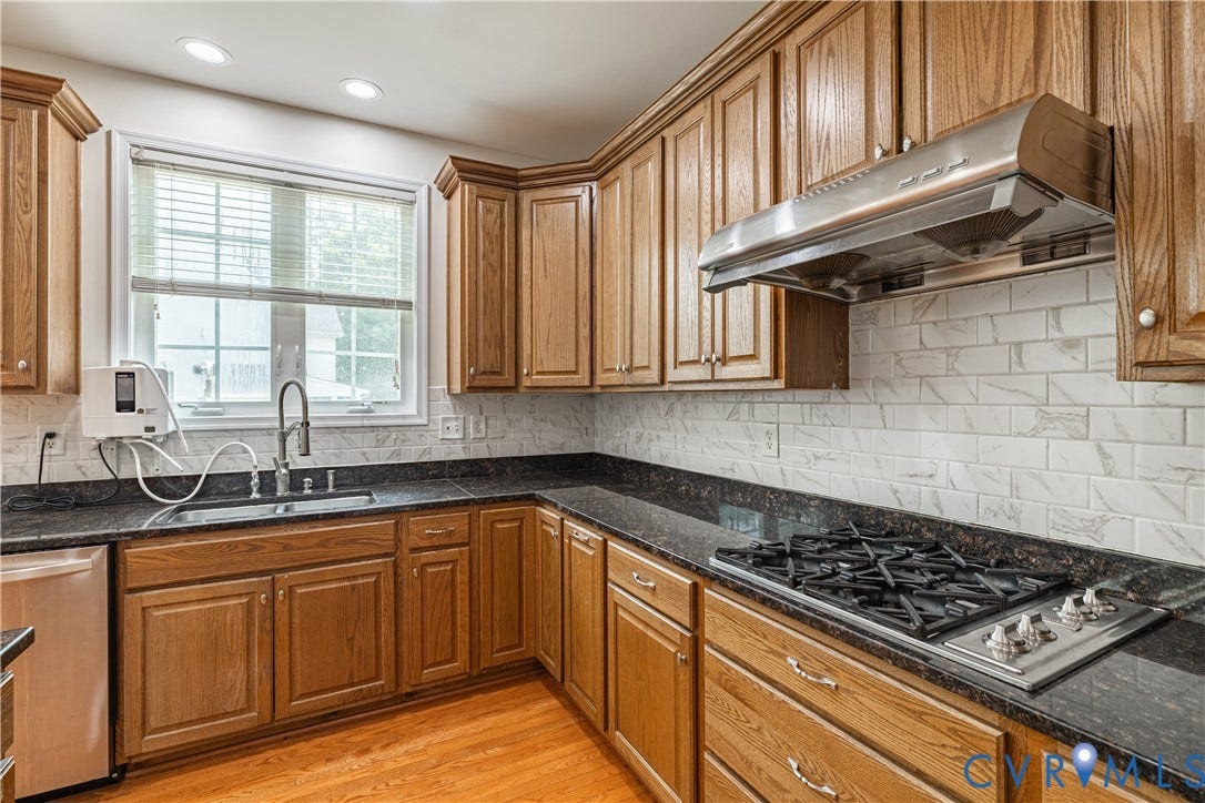 16814 Jennway Place, Moseley, VA 23120 Kitchen featuring wood cabinetry, dark countertops, a stainless steel gas cooktop, a stainless steel range hood, and a subway tile backsplash