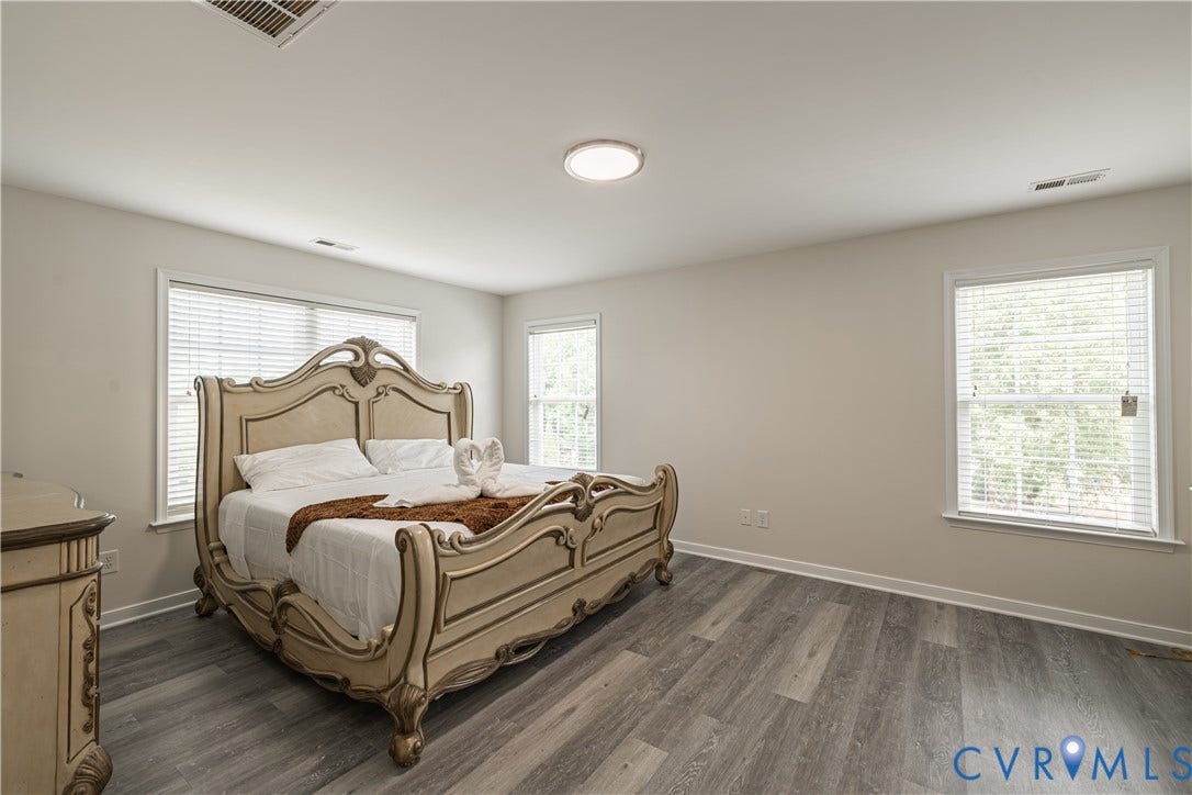 16814 Jennway Place, Moseley, VA 23120 Spacious room featuring wood-finish flooring, light-toned walls, and multiple windows with blinds