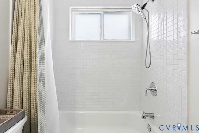 Built-in bathtub featuring subway tile surround, chrome fixtures, and a sliding window
