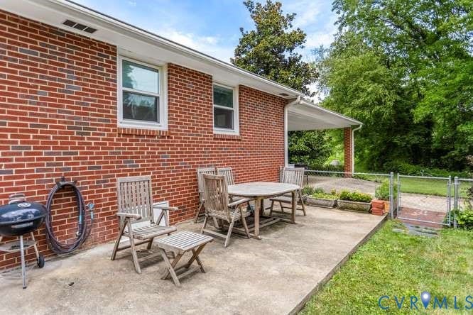 Red brick exterior featuring white-framed windows, a concrete patio, and a covered porch area