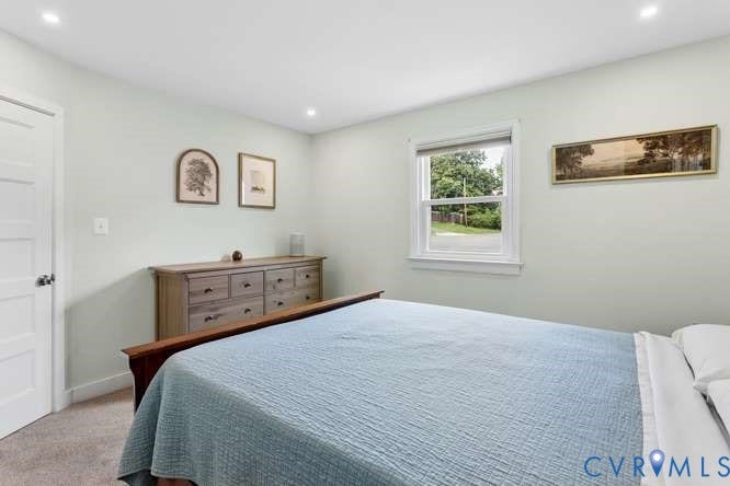 Bedroom featuring light-toned walls, recessed lighting, carpet flooring, and a multi-pane window with white trim