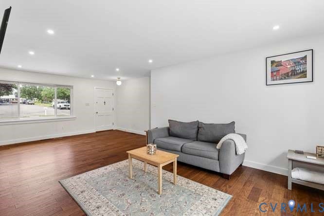 Expansive living space featuring wood-finish flooring and recessed ceiling lighting