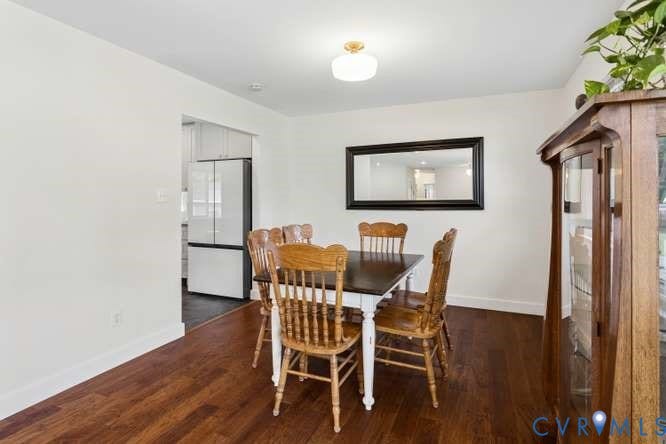 Dining area featuring wood-finish flooring, a contemporary ceiling light fixture, and an opening to the kitchen