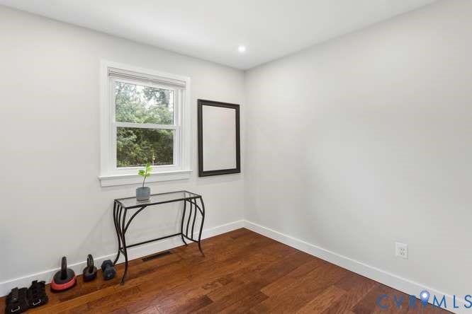 Bright interior space featuring a window with white trim, wood-finish flooring, recessed lighting, and crisp white walls