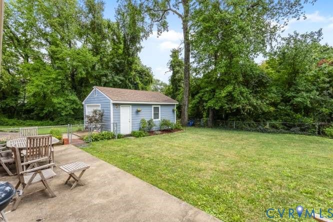 Expansive concrete patio offering generous outdoor living space, complemented by a detached shed with light blue siding and a brown roof