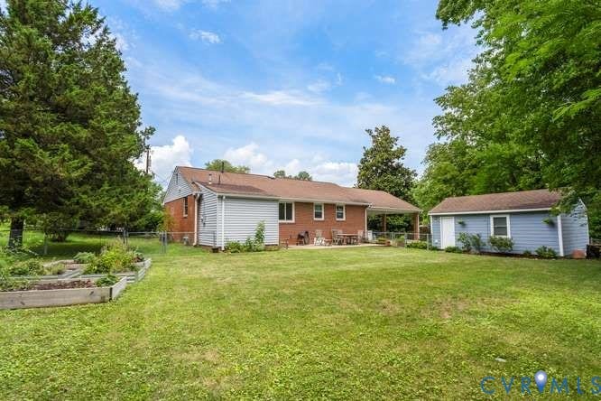 Expansive rear yard featuring a large lawn area, a covered patio, and a detached storage shed