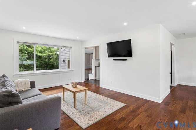 Hardwood flooring spanning the room, recessed lighting, and a large picture window providing natural light