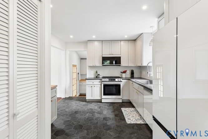 Modern kitchen featuring hexagonal floor tiles, white cabinetry, integrated stainless steel appliances, and recessed lighting